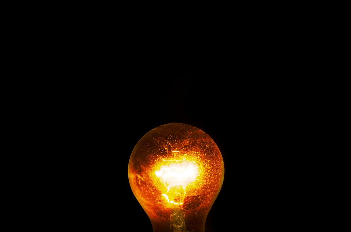 A single incandescent bulb glowing warmly against a dark background