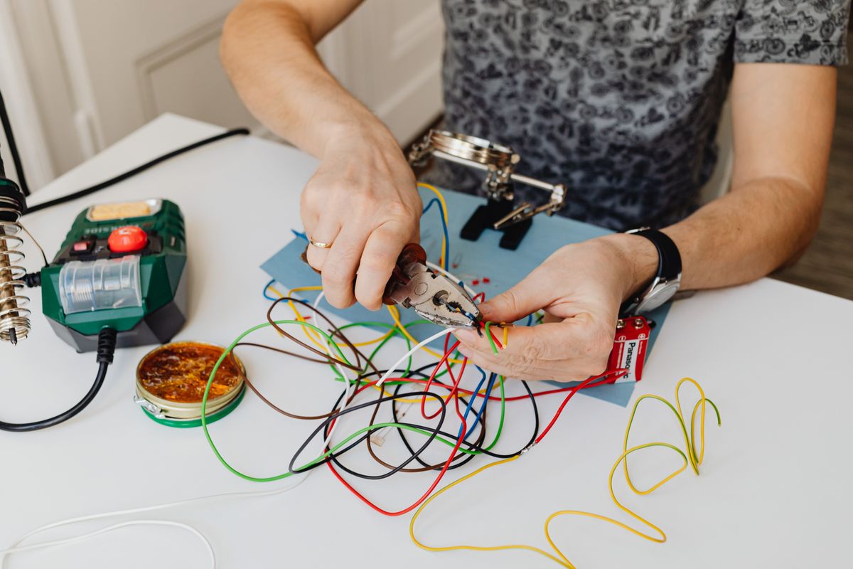 Close-up of hands trimming and sorting colorful electrical wires with pliers